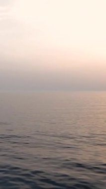 Deniz manzarasının dingin güzelliğine dalın, sakin sularda zahmetsizce süzülen beyaz bir tekne gibi, narin köpükler oluşturarak ve bu deniz yüzeyindeki canlı güneş ışığını yansıtarak.