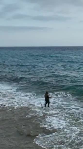 この垂直ビデオで撮影された冬の風景を歩き バレーボールをし 釣りをし 楽しむなど さまざまなレジャーの追求に従事する人々としてビーチシーンに突入します — ストック動画