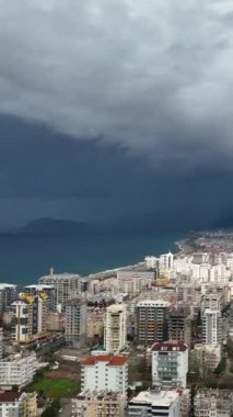 Fırtınalı Akdeniz kıyı şeridine ve şehir panoramasına bu dikey videoda havadan bakarken sahil uyarısına kulak verin..