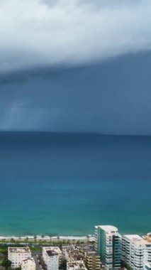 Fırtınalı Akdeniz kıyı şeridine ve şehir panoramasına tanıklık ederken sahilin kroniklerine dalın ve bu dikey videoda yoğun bir uyarı eşliğinde.