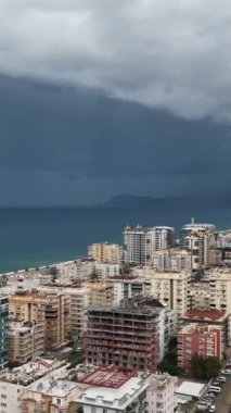 Fırtınalı Akdeniz kıyı şeridinin ve şehir panoramasının büyüleyici hava manzarasına doğru kaçın. Bu dikey videoda atmosferik uyarıya dalın..
