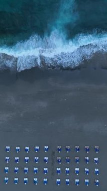 Fırtınalı denizin bir sahil kafesini ve boş güneşlikleri çevrelediği ve bu dikey videoda çalkantılı atmosferi yakaladığı kaotik sahneyi izleyin..