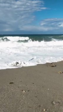Sabah fırtınası ve güçlü dalgalar arasındaki çarpışmaya tanık olun. Sahildeki engebeli kayalarla şiddetli bir şekilde savaşıyorlar. Bu dikey videoda yukarıdan büyüleyici bir görüntü sunuyorlar..