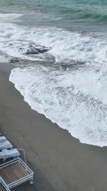 海岸の年代記に飛び込み 朝の嵐と岩の多いビーチの荒々しさに対する強力な波を目撃し この垂直ビデオで魅惑的な物語を明らかにしてください — ストック動画