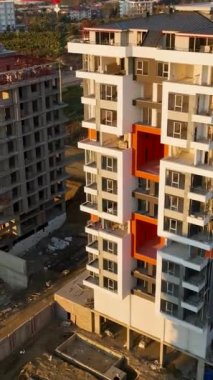 Yukarı doğru süzül ve inşaat alanlarının lüks çok katlı dairelere dönüştükçe binanın panoramik manzarasını izle. Bu dikey videoda benzersiz bir bakış açısı sağlıyor..