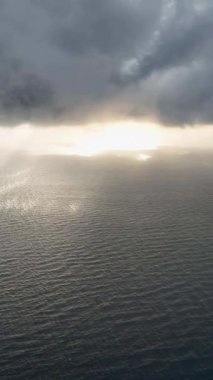 Bulutlar arasında büyüleyici bir yolculuğa çıkın. İnsansız hava aracı, bu dikey videoda deniz ve şehirde dramatik bir günbatımının ilham verici güzelliğini yakalar..