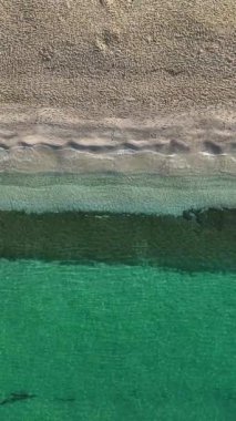 İnsansız hava aracı, sakin bir sahili masmavi sularla kuşbakışı izleyip bu büyüleyici dikey videoda sükunet hissi uyandırırken, kendinizi kıyı kaçışına daldırın..