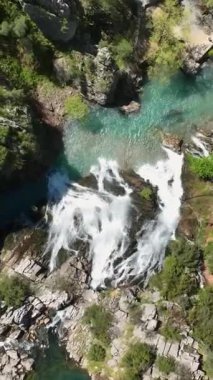 İHA 'nın sinematik cazibesini yakalayıp sizi görsel bir yolculuğa davet ettiği gökyüzü perspektifi ile büyüleyici bir şelalenin sinematik sihrini ve gök mavisi sularını deneyimleyin.