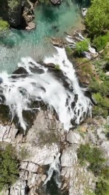 Sevilen bir turistik bölgede bulunan ikonik bir şelalenin kuş bakışı görüntüsünü alın. Havadan çekilen görüntüler çağlayan suyun ihtişamını ve etrafındaki manzaranın cazibesini göstersin.