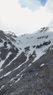 Seyircilerinizi, karlı zirveler ve dramatik bulutlarla süslenmiş muhteşem bir dağ silsilesinin hayranlık uyandıran hava görüntüsüyle eğlendirin. Dikey videonuzu bu büyüleyici manzarayla yükseltin.