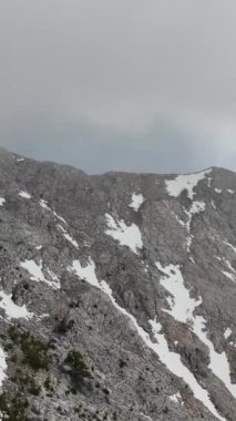 Bir dağ vadisinin dinginliğini, hayranlık uyandıran hava manzaralarıyla yaşayın. Dikey videonuzda karla kaplı tepelerin ve canlı yeşilliğin büyüleyici bir karışımını yakalayın.