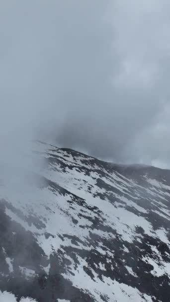 走进一个迷人的世界 在空中拍摄到一个宏伟的山脉 有着雪峰和戏剧性的云彩 让你的观众在你的垂直方向上进入一个美丽和惊奇的境界 — 图库视频影像