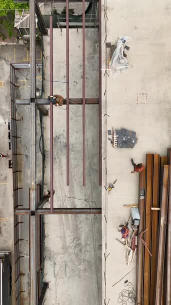 在这个垂直的视频中 可以看到建筑区域的全景航空图 观察熟练的建筑工人在建造一个巨大的零售综合设施时卸下和放置金属梁的情况 — 图库视频影像