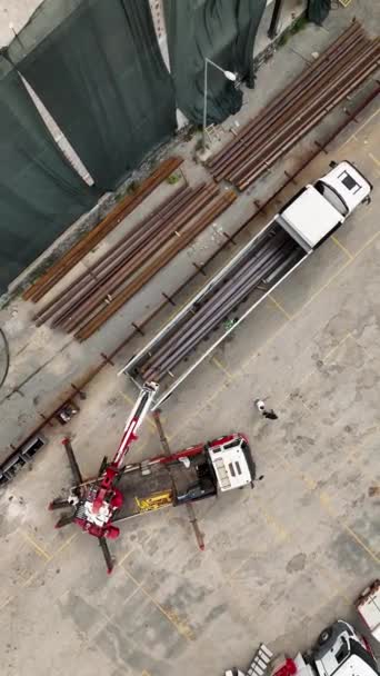 この垂直ビデオで賑やかな建設活動を垣間見ることができます 労働者が活気のあるショッピング目的地で鋼の梁をアンロードし 慎重に位置するように見る — ストック動画