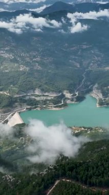 Bu dikey videoda büyüleyici bir su deposunun büyüleyici güzelliğini keşfettiğinizde bulutlarla örtülü bir dağ manzarasında keyifli bir hava keşfine çıkın. Doğal ihtişam