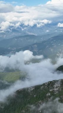 Kendinizi bu dikey videoda bulutlarla süslenmiş bir dağ manzarasının nefes kesici güzelliğine daldırın. Yükselen zirvelerin ihtişamına ve mavi bulutların ruhani dansına tanık olun.
