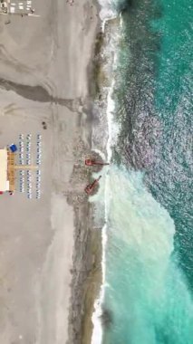 Kıyı şeridinin dinamik dönüşümünü deneyin. Ağır makineler titizlikle taş plajı yontuyor ve deniz yüzeyinde büyüleyici bir gök mavisi izi oluşturuyor..