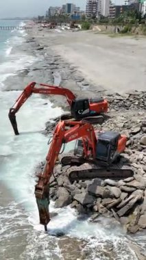 Taştan kumsaldaki ağır makineler tarafından dönüştürülen doğal tuvalin kuşbakışı görüntüsünü alın. Çevredeki deniz manzarasıyla harmanlanan büyüleyici bir gök mavisi izi yaratın..