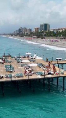 Gökyüzünde süzülen bir iskele cennetinin huzurlu atmosferini yakalayın, iskele boyunca dizilmiş şezlonglara hayran kalarak..