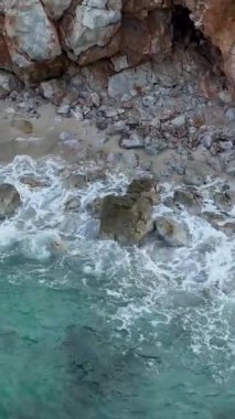 Gök mavisi suların engebeli kayalarla buluştuğu el değmemiş bir plajın nefes kesici güzelliğini keşfedin..