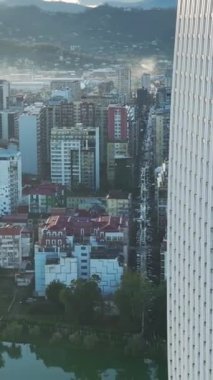 Gürcistan 'ın Batumi kentinin panoramik bir manzarasını keşfedin, Karadeniz' in arka planına karşı inşa edilmiş cam önlü gökdelenleri.