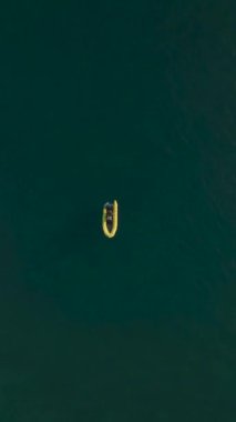 4K yüksekliğinde Akdeniz cankurtaranıyla uçarak, denizin mavi ufkunun ortasındaki şişme bir tekneyi gözlemlemek..