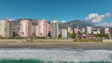 Deniz kenarında beyaz bir bina gösteren 4K hava görüntülerine bir bakın. Gök mavisi denizin çarpıcı manzarası.