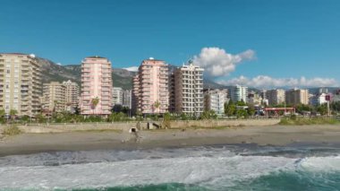 4K insansız hava aracı görüntülerinde deniz kenarında beyaz bir bina gözlemleyin. Gök mavisi denizin havadan detaylı manzarası.