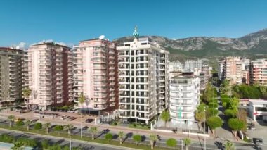 Büyük bir Akdeniz kompleksinin panoramik 4K görüntüsü mavi havuz ve beyaz cephe.