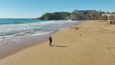 4K hava görüntülerinde Akdeniz sahilinde siyah giyen bir adamın ilginç gölgesini izleyin..