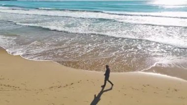 4K açıklığında Akdeniz 'in kumlu kıyılarında dolaşan siyahlı adamı takip edin..