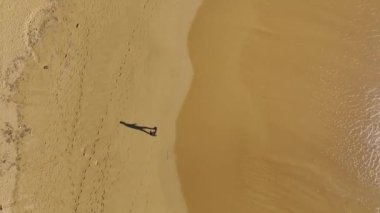 Akdeniz sahilinde gün batımında 4K 'da yakalanan siyahlı bir adamın esrarengiz yürüyüşüne katıl..