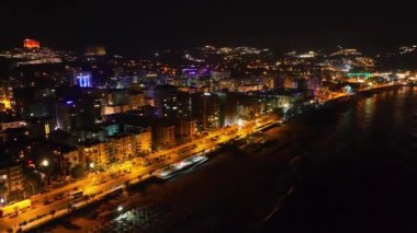 Gece vakti aydınlık binaları ve geceleri parlayan caddeleri olan şehir manzarasını izle..