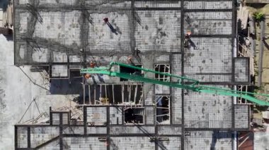 Demir büken ve beton döken işçileri gözlemleyin. Bina için sağlam bir temel oluşturuyorlar..