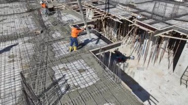 İnşaat alanında beton döken ve demiri şekillendiren işçiler, bir binanın temelini oluşturuyorlar..