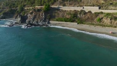 Üstü açık beyaz bir arabanın dağ yollarında dolaştığını ve büyük bir nehir köprüsünü geçtiğini görüyorum..