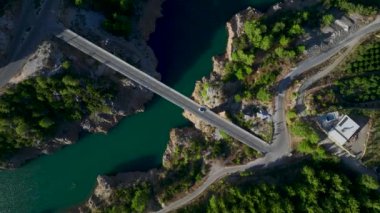 Üstü açık beyaz bir arabanın köprüden geçişini ve dağlarda yolculuk edişini izleyin..