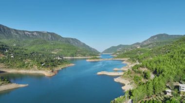 Aerial View 4K: Nehir Üzerindeki Beyaz Üstü Açık Yolculuk ve Dağ Geçitleri
