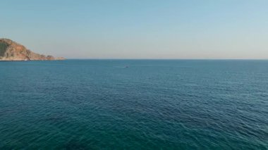 Güneş arka planda batarken sakin sularda hızla ilerleyen bir spor teknesini izleyin..
