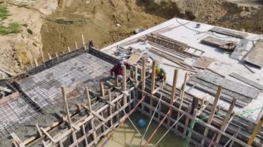 İşçiler yeni bir yapının temelini tamamlarken yoğun bir şekilde beton döküyorlar..