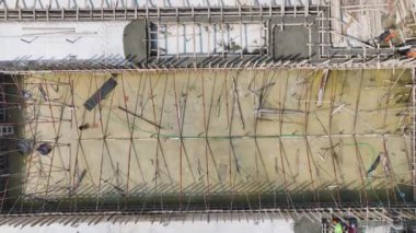 İşçiler yoğun bir inşaat sahasına beton dökerek yapının temelini oluşturuyorlar..