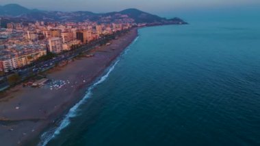 Şehir ve günbatımının ufukta parladığı deniz manzarasının tadını çıkar..