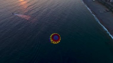 Gün batımında deniz paraşütünün güzelliğini izleyin, şehir arka planda parlarken..