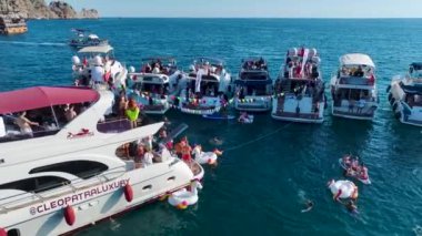 Açık denizdeki bir yat festivalinde yüksek sesli müzikle dans eden insanları izleyin. Bir DJ ortamı yönetiyor..