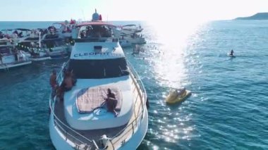 Açık sularda dans eden kalabalık ve yüksek sesli müzik çalan bir DJ 'in olduğu bir yat festivali seyredin..