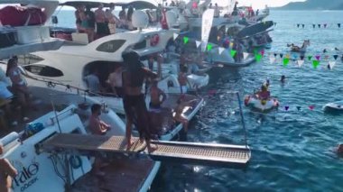 Canlı bir yat festivali seyret. DJ, müzik ve açık denizde dans eden insanlar..
