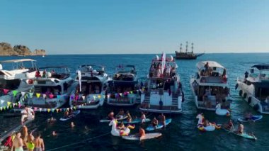 İnsanlarla dolu yatları izlemek ve açık denizde bir yat festivali sırasında DJ 'in müzik çalması..