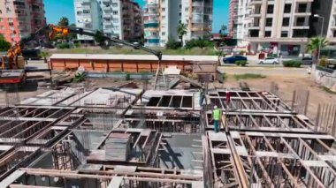 İnşaat işçileri yeni bir binanın temelini hazırlamak için inşaat demirini sıkıca bağlıyorlar..