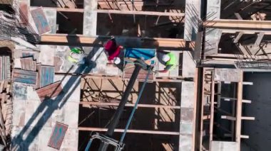 Büyük bir inşaat alanının inşaatını güçlendirmek için inşaat demirini bağlayan işçileri izleyin.