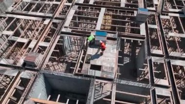 Yeni bir yapının dayanıklılığını ve istikrarını sağlamak için inşaat demirini koruyan işçileri izleyin..